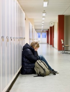Young woman crying by the lockers at school