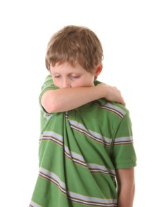 boy coughing into arm