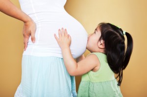 Girl kissing pregnant mother