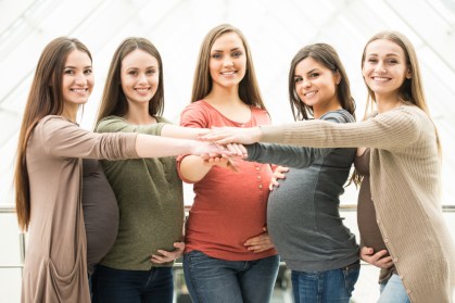 Portrait of five happy, friendly pregnant women are looking at the camera.