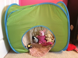 A child's tent filled with pillows and stuffed animals