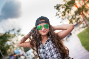 Portrait of smiling teenage girl with hands behind her head looking at the camera.