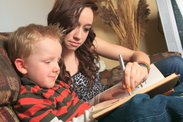 Babysitter and little boy write in book together