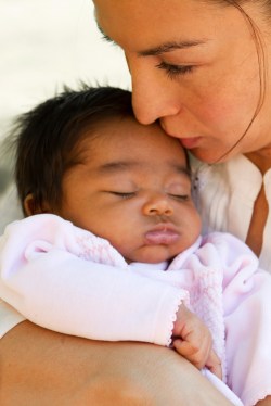 Mother kissing sleeping baby in arms