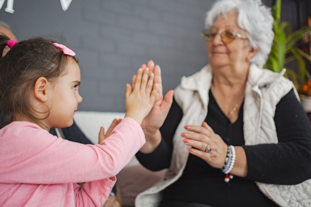 Grandmother clapping hands with granddaughter.