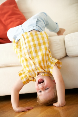Silly toddler boy upside down hanging off couch