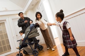 Parents are late trying to get out the door while mother pulls little girl's hand to hurry up