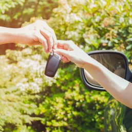 young smiling woman sitting in car taking key