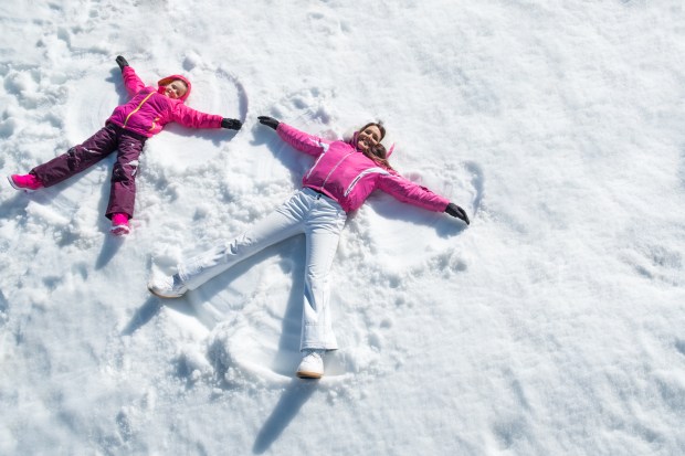 Mother and daughter happily making snow angels in the snow