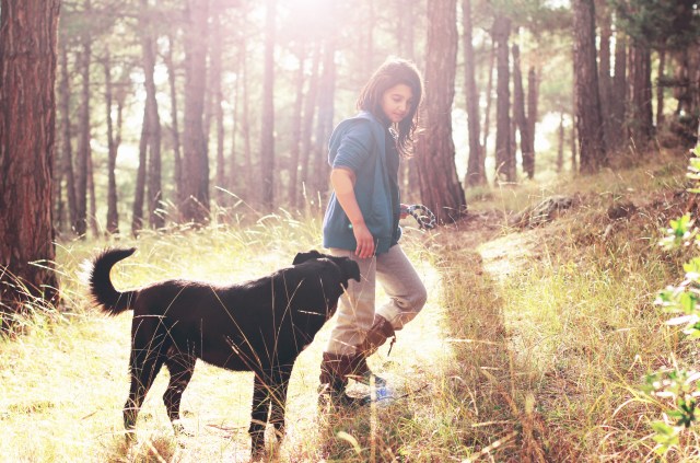 Girl walking with dog in nature.