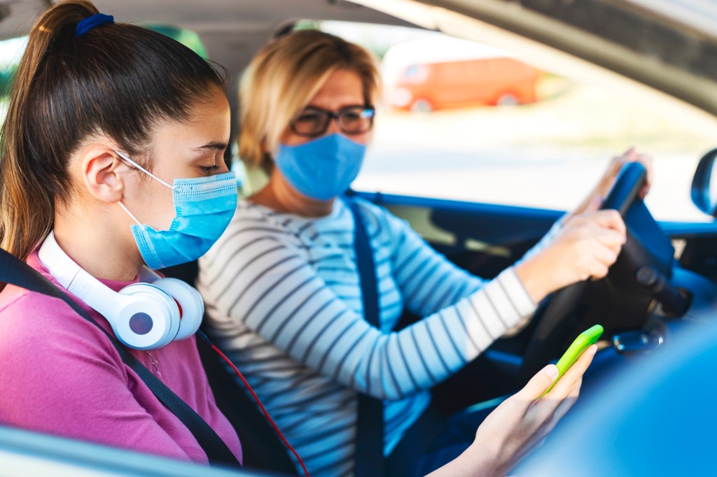 Mom and daughter in car wearing face masks.