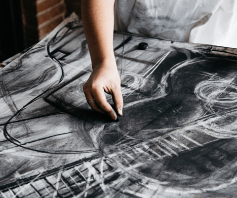 Person sketching artwork with chalk